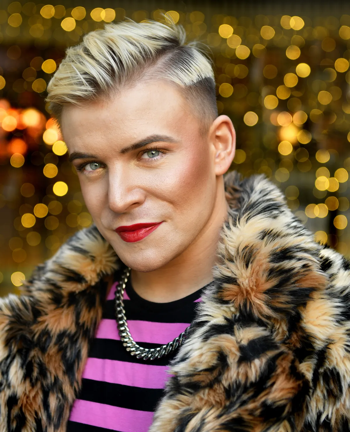 Ollie in a leopard print faux fur coat against golden lights