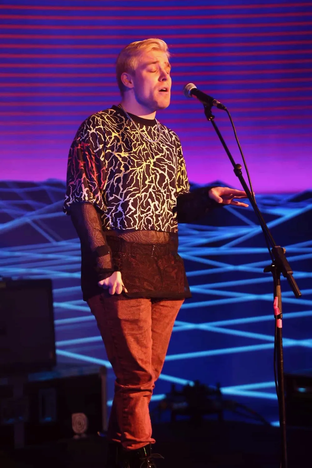 Ollie singing live in front of a purple stage backdrop