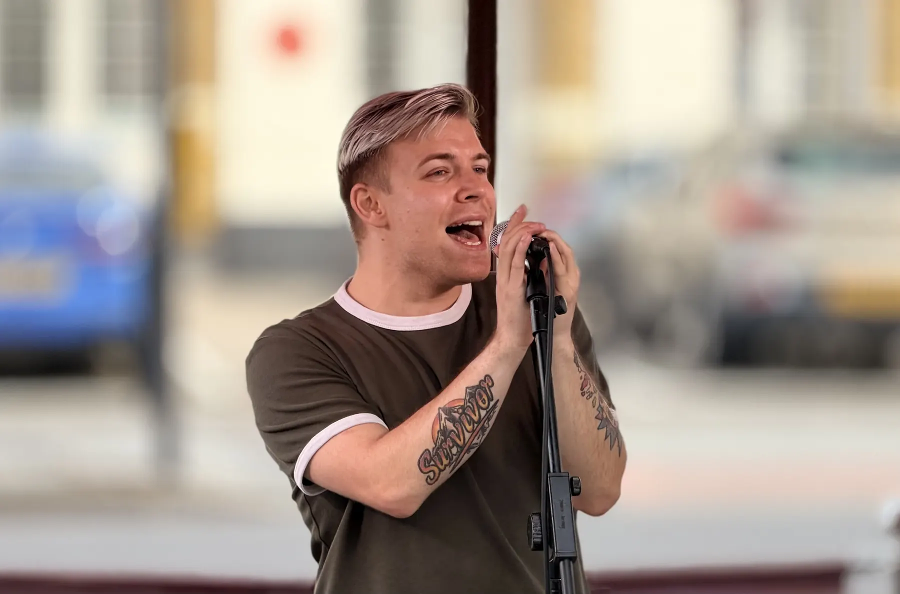 Ollie singing live outdoors, his Survivor tattoo on his forearm